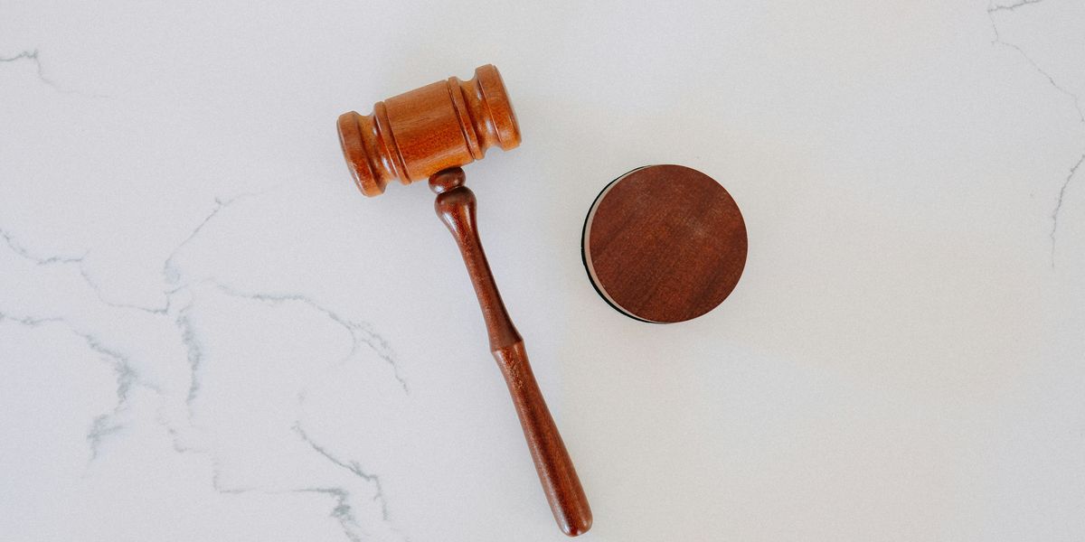 Brown wooden gavel on white marble surface.