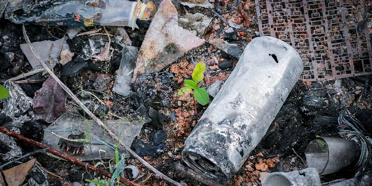 Burned plastic waste on the ground after a wildfire.