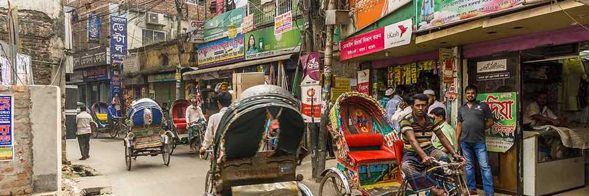 Busy street in Dhaka Bangladesh with brick buildings and rickshaws in the street