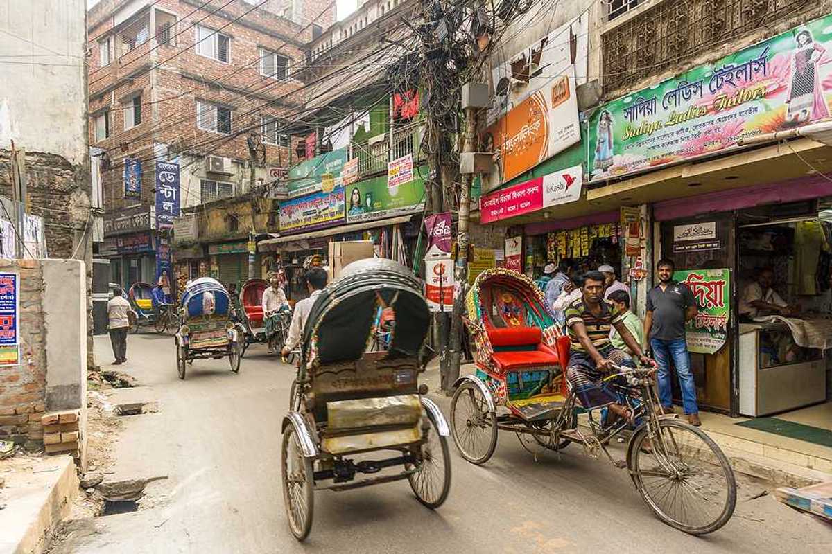 Busy street in Dhaka Bangladesh with brick buildings and rickshaws in the street