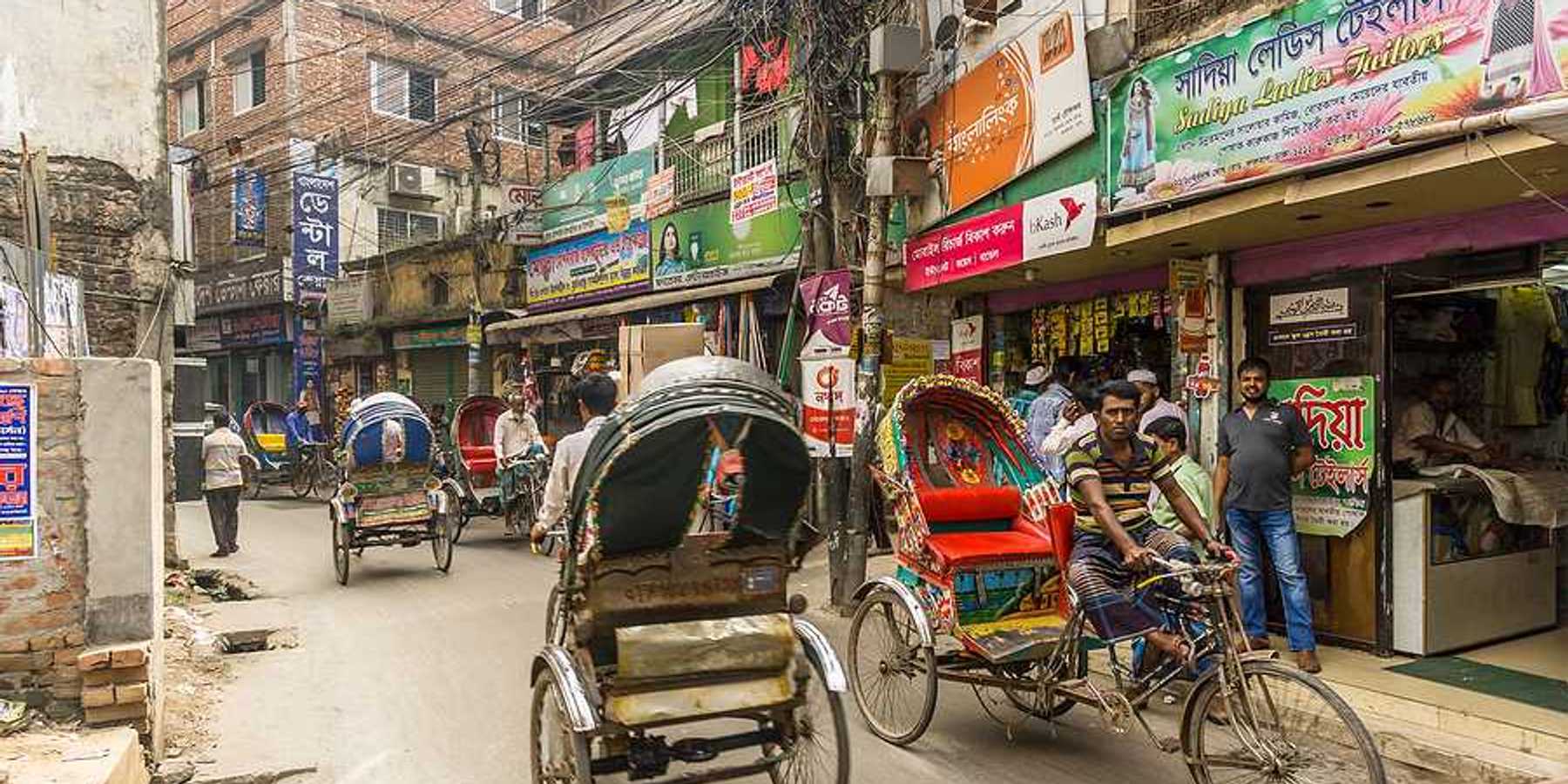 Busy street in Dhaka Bangladesh with brick buildings and rickshaws in the street