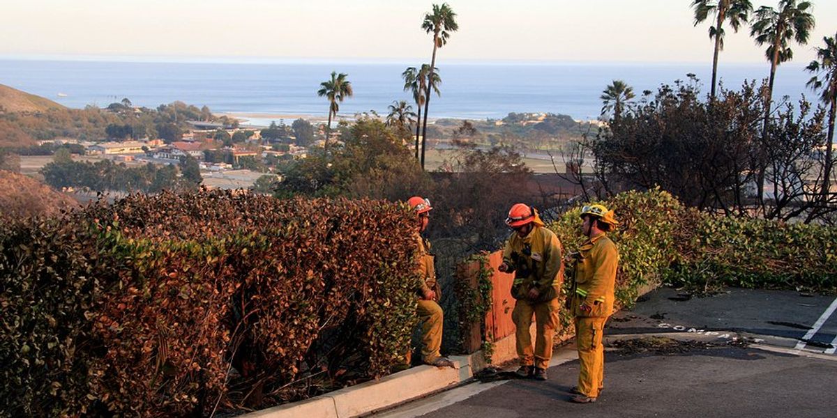California firefighters looking out over a smoky ridge toward the ocean.