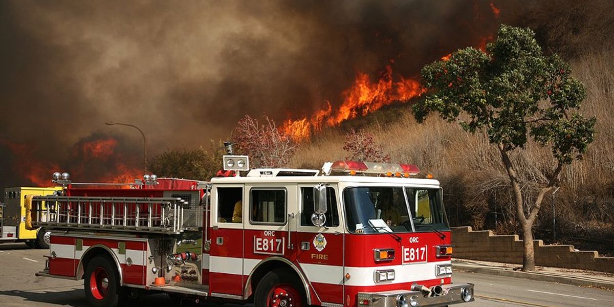 California firetruck in front of a burning hillside.