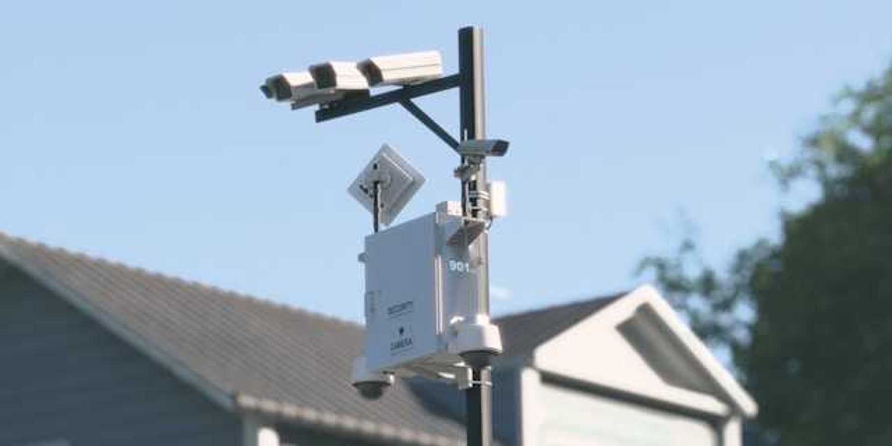 Cameras mounted on a tall pole with a house in the background
