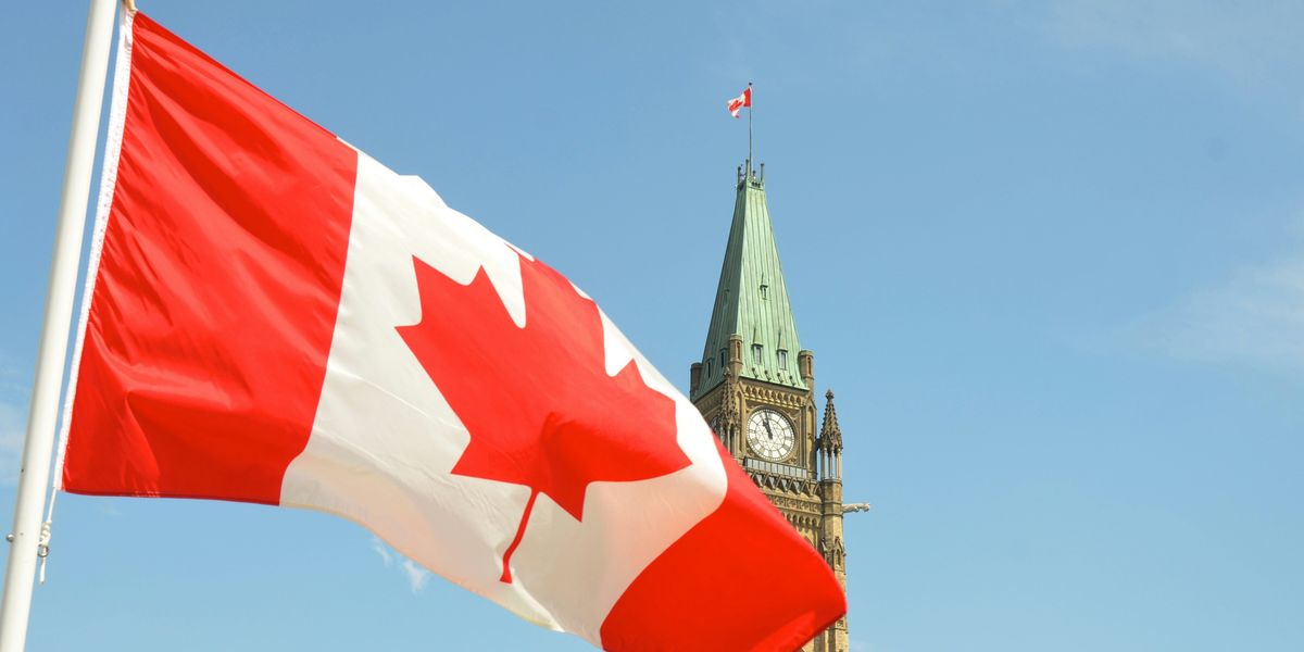 Canadian flag on a sunny day waving in front of the Canadian parliament building