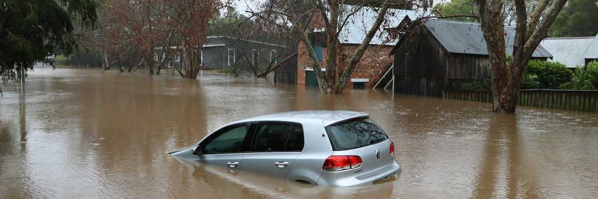 Car bobbing in brown floodwaters on flooded street in flooded neighborhood