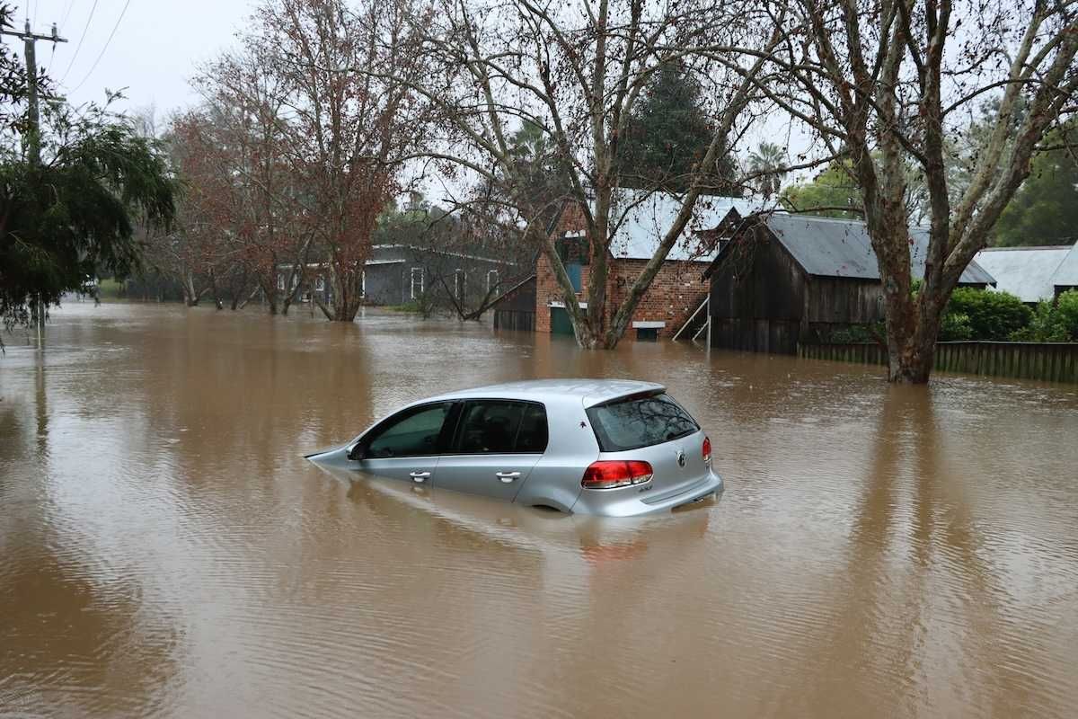 Car bobbing in brown floodwaters on flooded street in flooded neighborhood