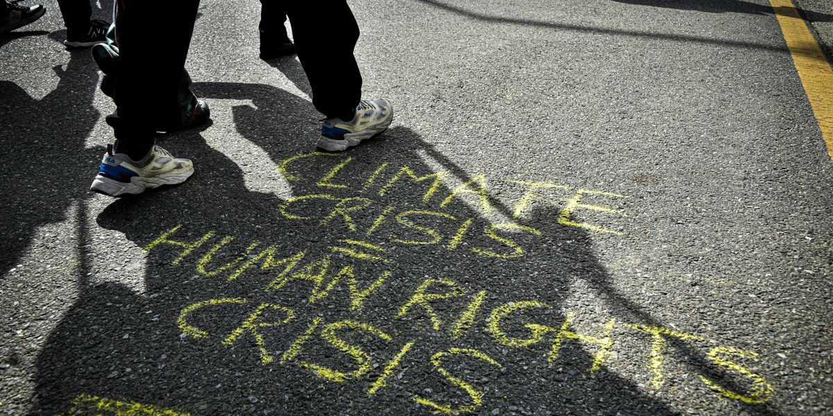 Chalk on the pavement saying Climate Crisis equals Human Rights Crisis.
