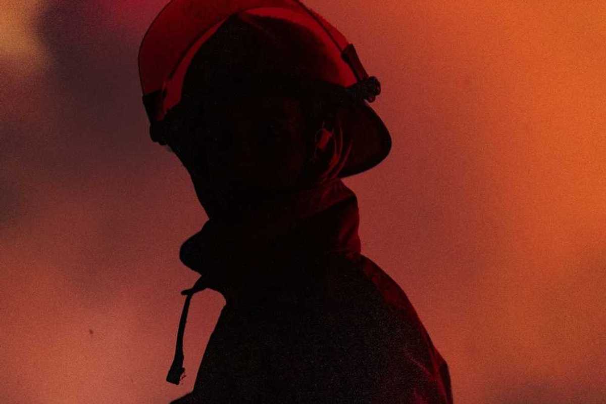 Chest-up view of firefighter in profile with mostly obscured face, faced towards the camera