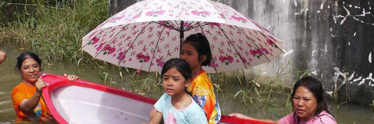 Children being transported through deep water in a small plastic dinghy during the monsoon flooding of October 24 2010 in Nakhon Ratchasima Thailand.