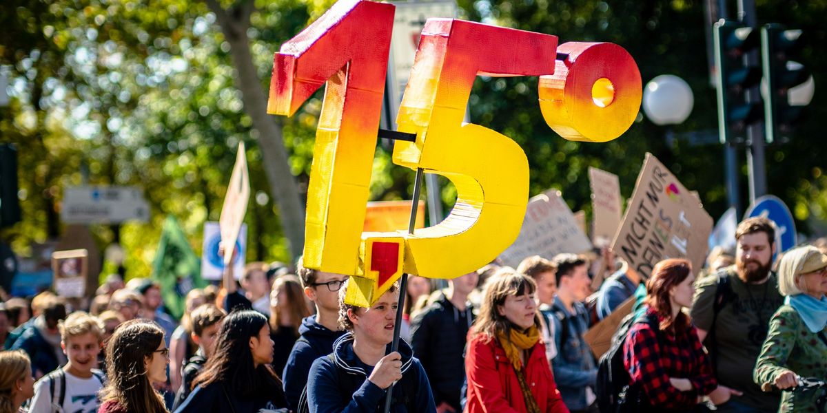 climate protestor holds up a 1.5 degree Celsius sign