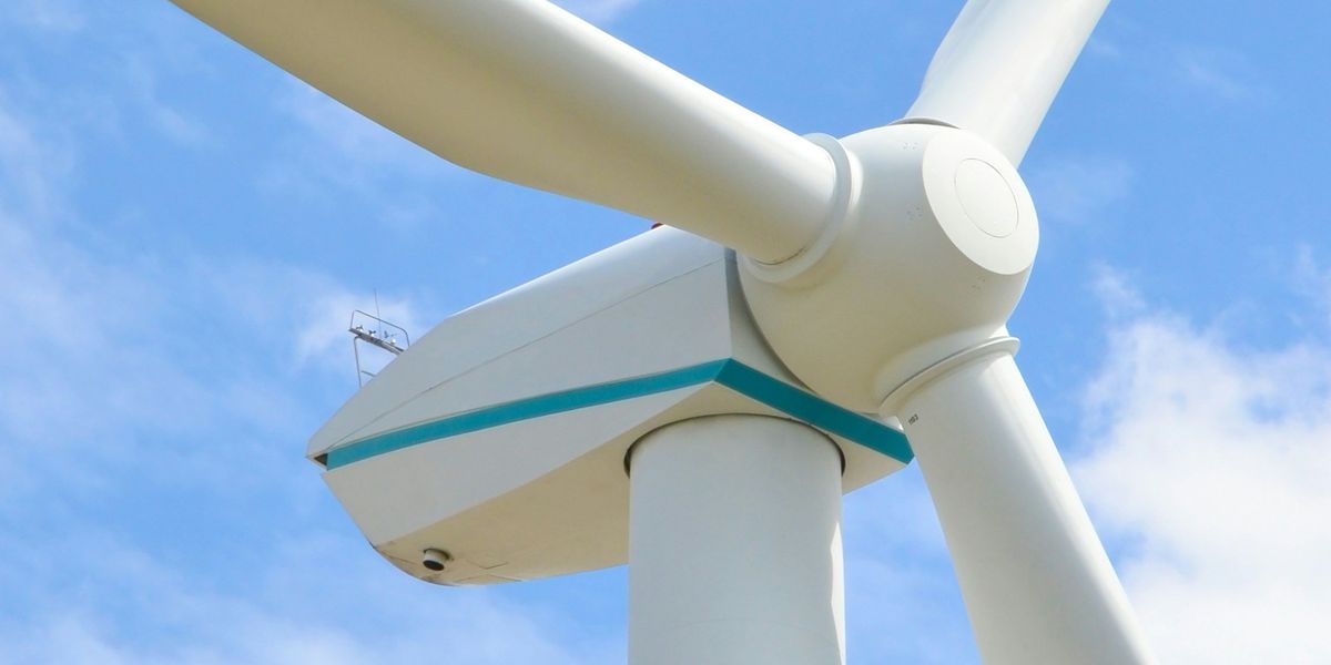 Closeup of a wind turbine with blue sky in the background.
