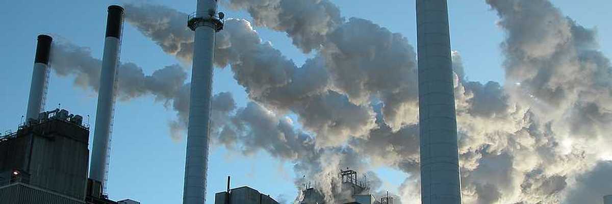 Coal plant with four smokestacks emitting pollution.