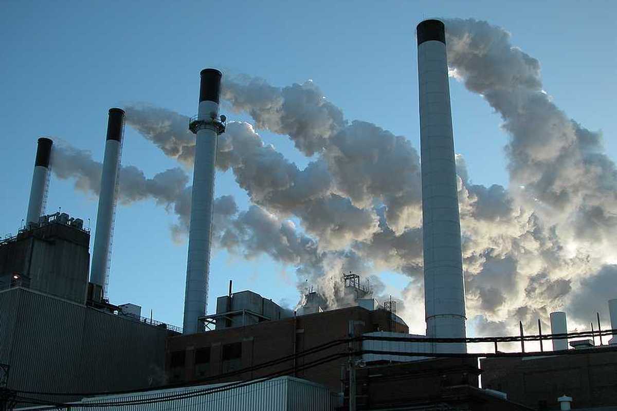 Coal plant with four smokestacks emitting pollution.