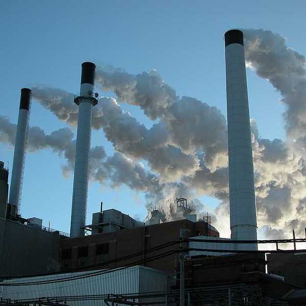 Coal plant with four smokestacks emitting pollution.