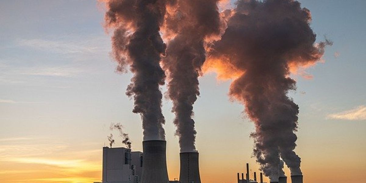Coal power plant with smoke rising from towers.