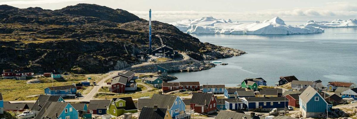 Coastal village in Greenland with multicolored homes and ice floes in the background