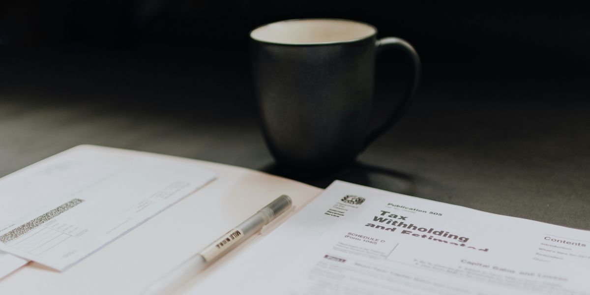 coffee mug near open folder with tax withholding paper.