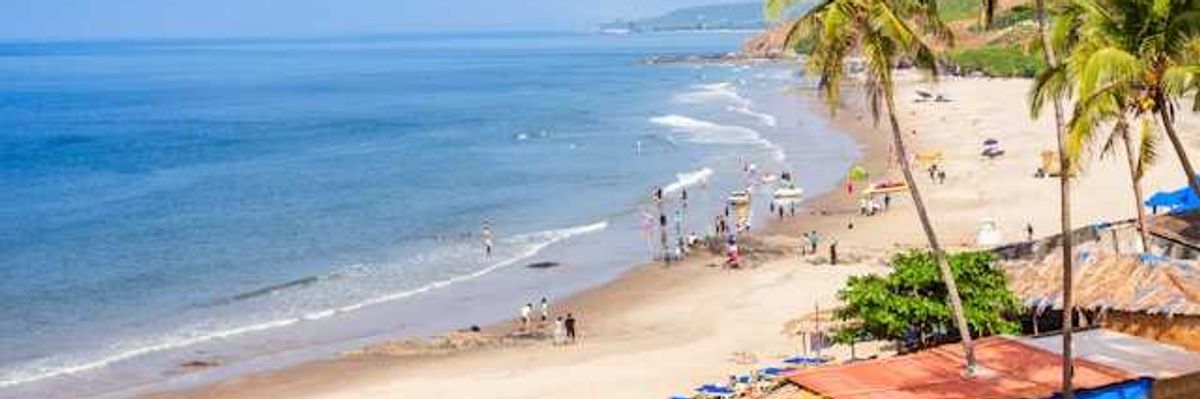 Colorful huts along a tropical beach with people on the sand