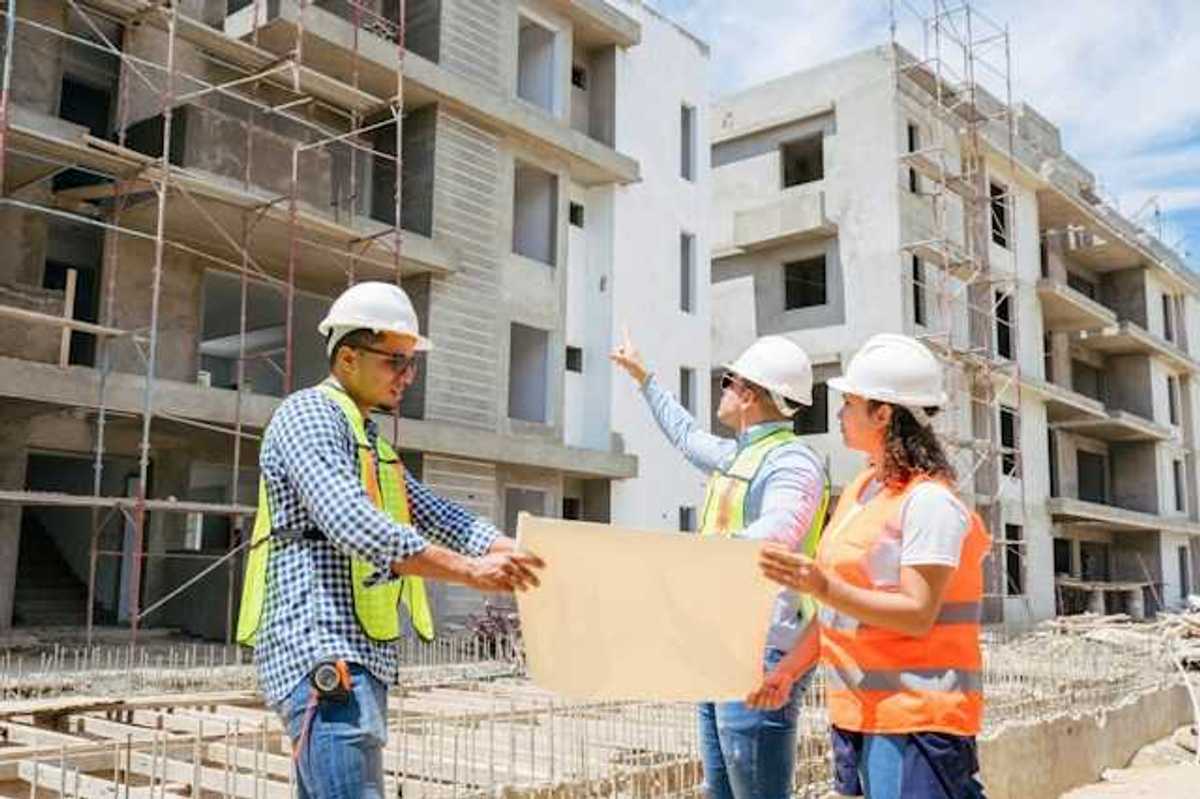 Construction managers looking at plans while viewing concrete buildings under construction