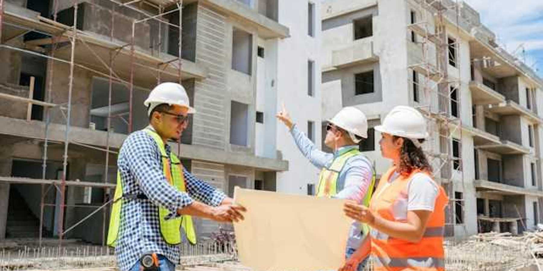 Construction managers looking at plans while viewing concrete buildings under construction