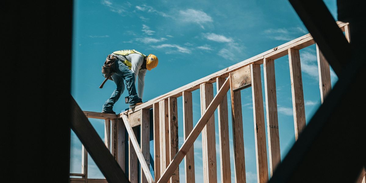 Construction worker standing on top of a wooden beam while working on a home build.