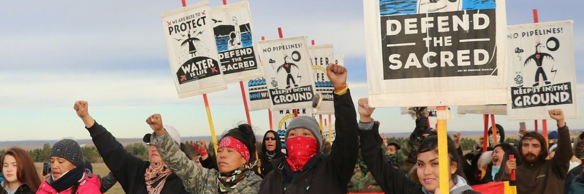 Dakota Access Pipeline protesters hold signs and raise fists.
