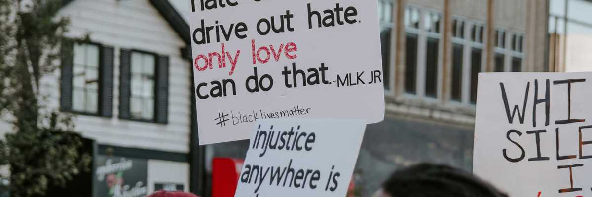 Demonstrators hold signs calling for racial justice.