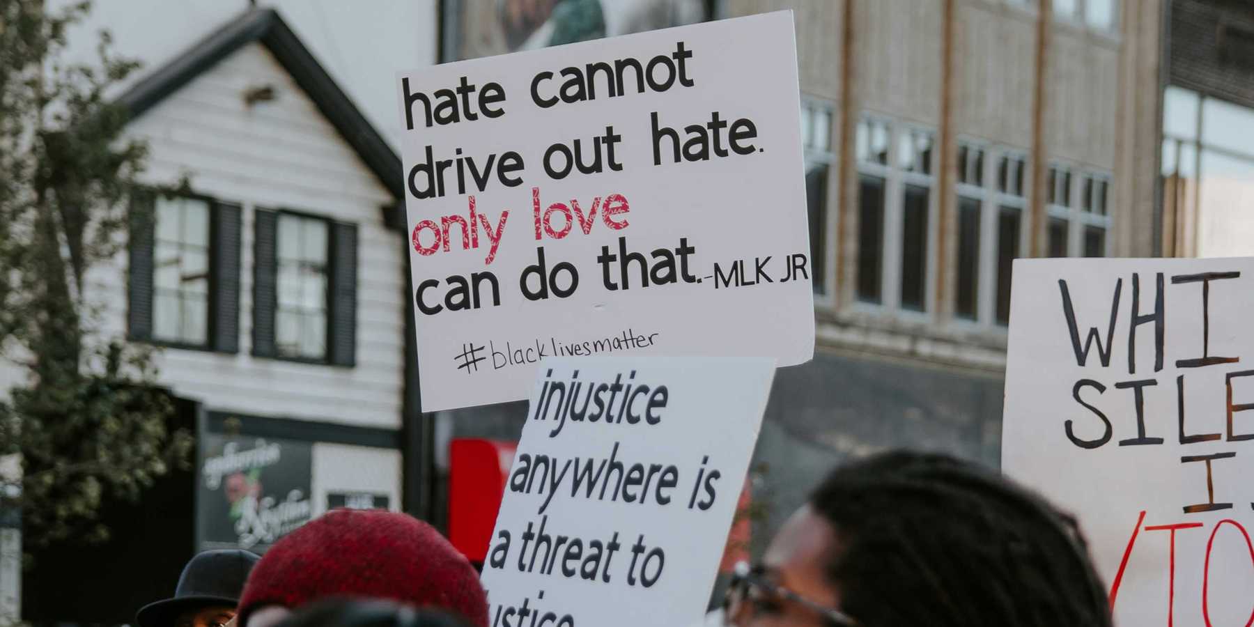 Demonstrators hold signs calling for racial justice.