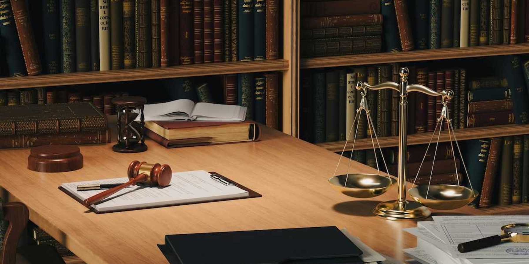 Desktop containing legal paperwork, gavel and scales representing justice