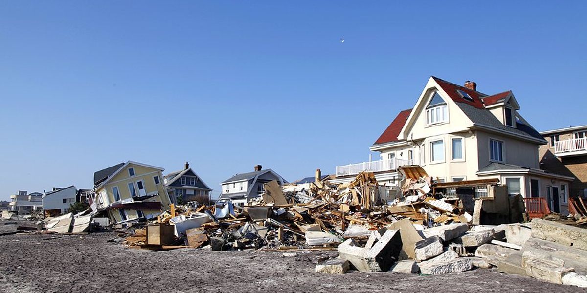 Destroyed houses on a beach with piles of debris.
