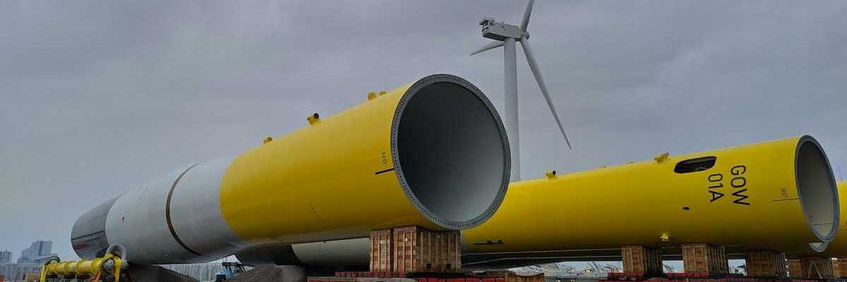 Dismantled yellow and white wind tower lying on the ground awaiting assembly