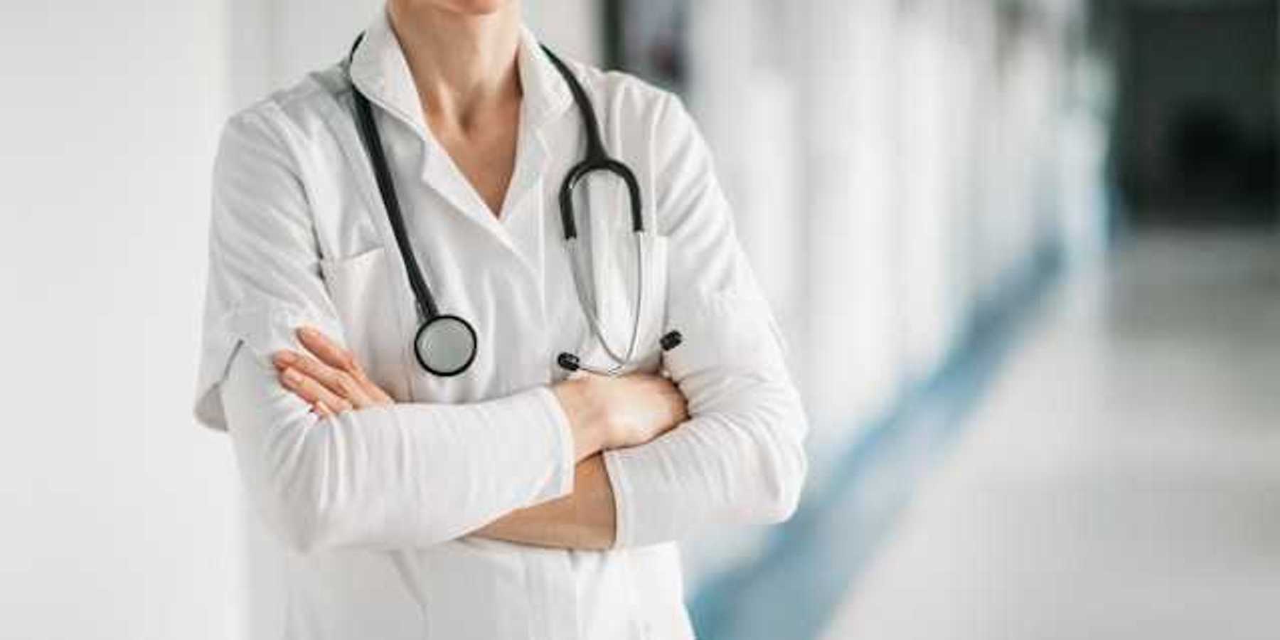Doctor standing with her arms crossed and smiling in a hospital hallway