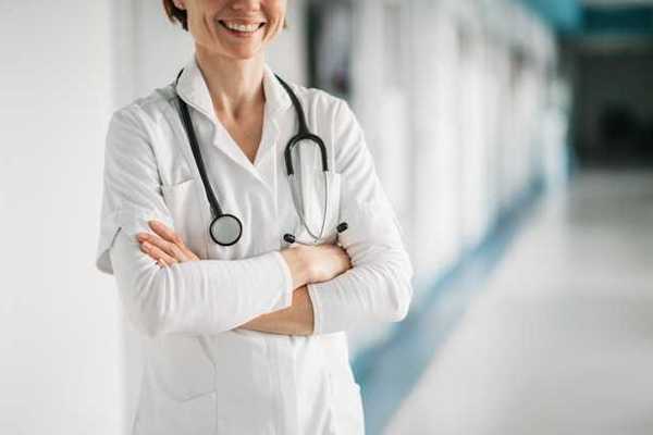 Doctor standing with her arms crossed and smiling in a hospital hallway