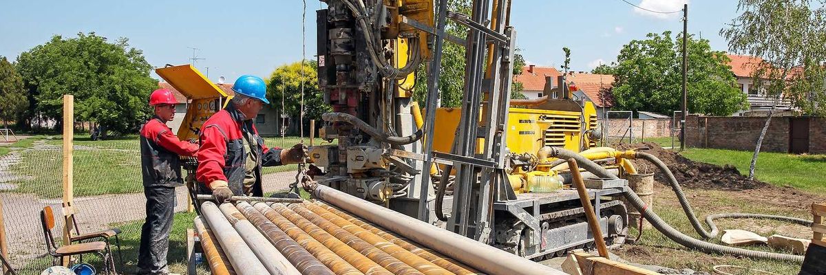 Drilling geothermal well for a residential geothermal heat pump. Workers on Drilling Rig.