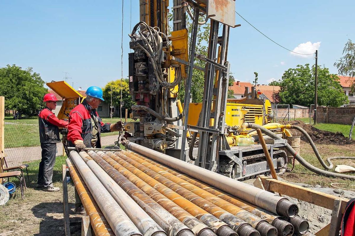 Drilling geothermal well for a residential geothermal heat pump. Workers on Drilling Rig.