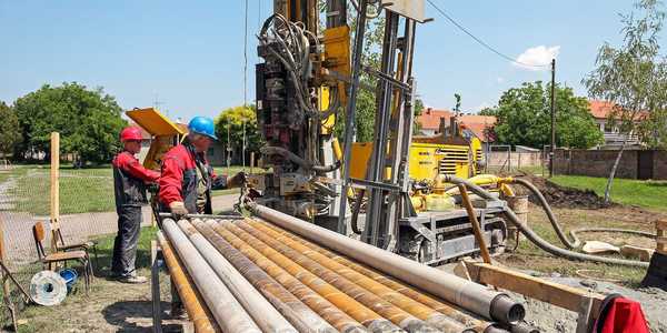 Drilling geothermal well for a residential geothermal heat pump. Workers on Drilling Rig.