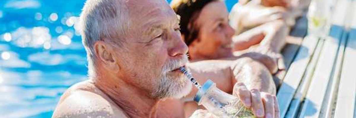 Elderly white man in a pool drinking from a straw