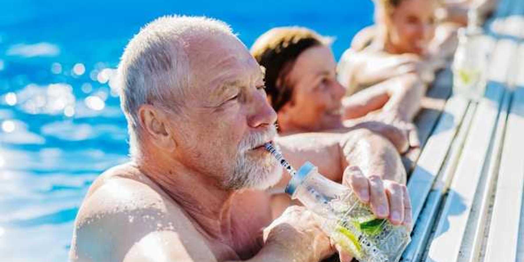 Elderly white man in a pool drinking from a straw