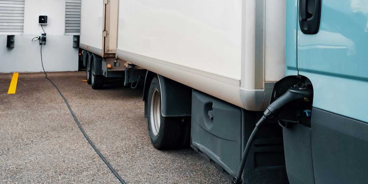Electric semi-truck connected to charger at loading dock