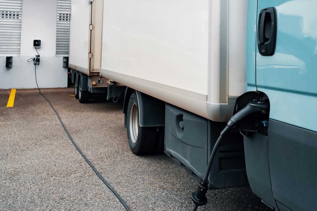 Electric semi-truck connected to charger at loading dock