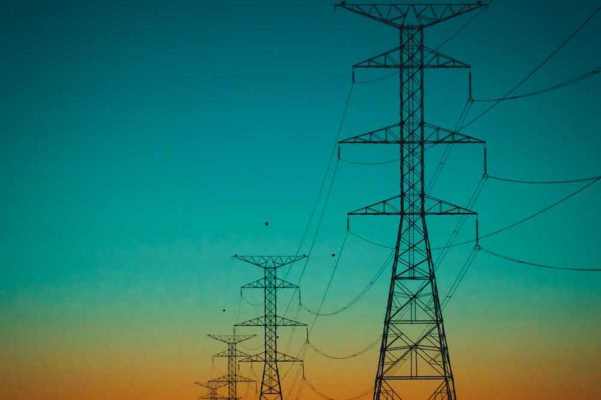 Electrical transmission lines against a rainbow-colored sky