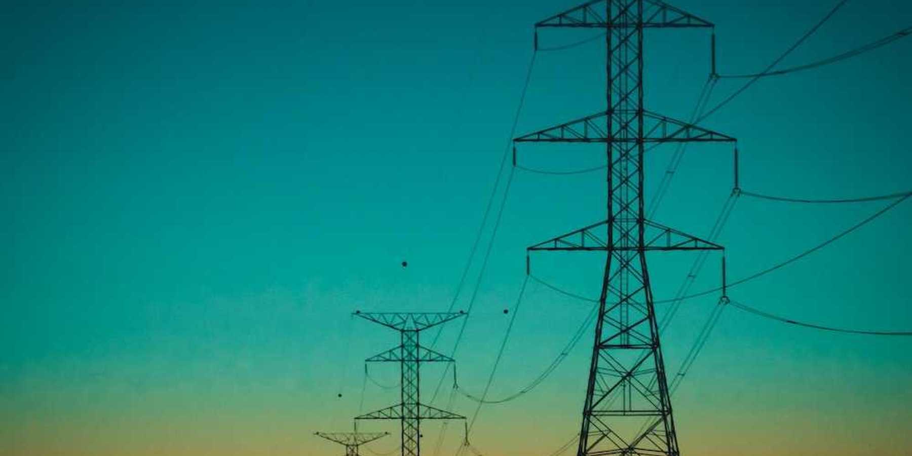 Electrical transmission lines against a rainbow-colored sky