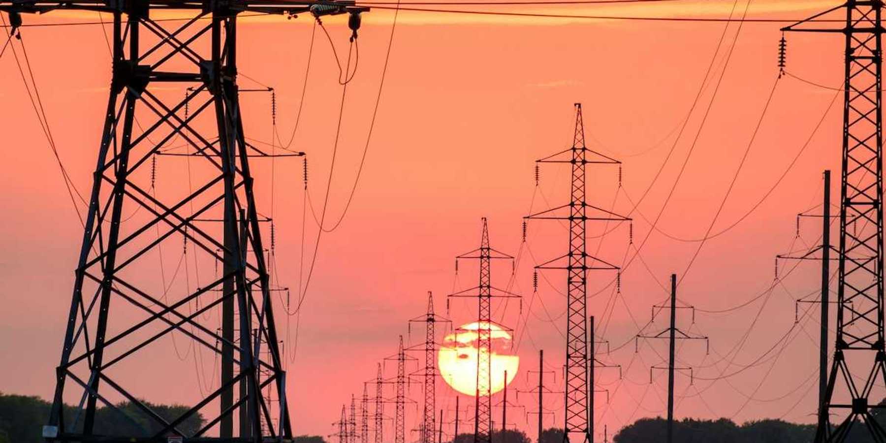 Electrical transmission lines silhouetted against setting sun