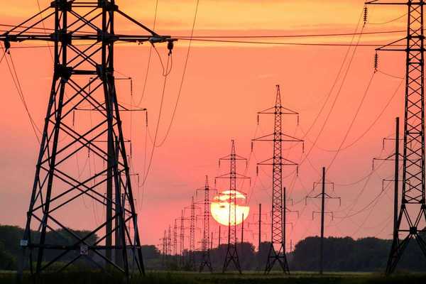 Electrical transmission lines silhouetted against setting sun