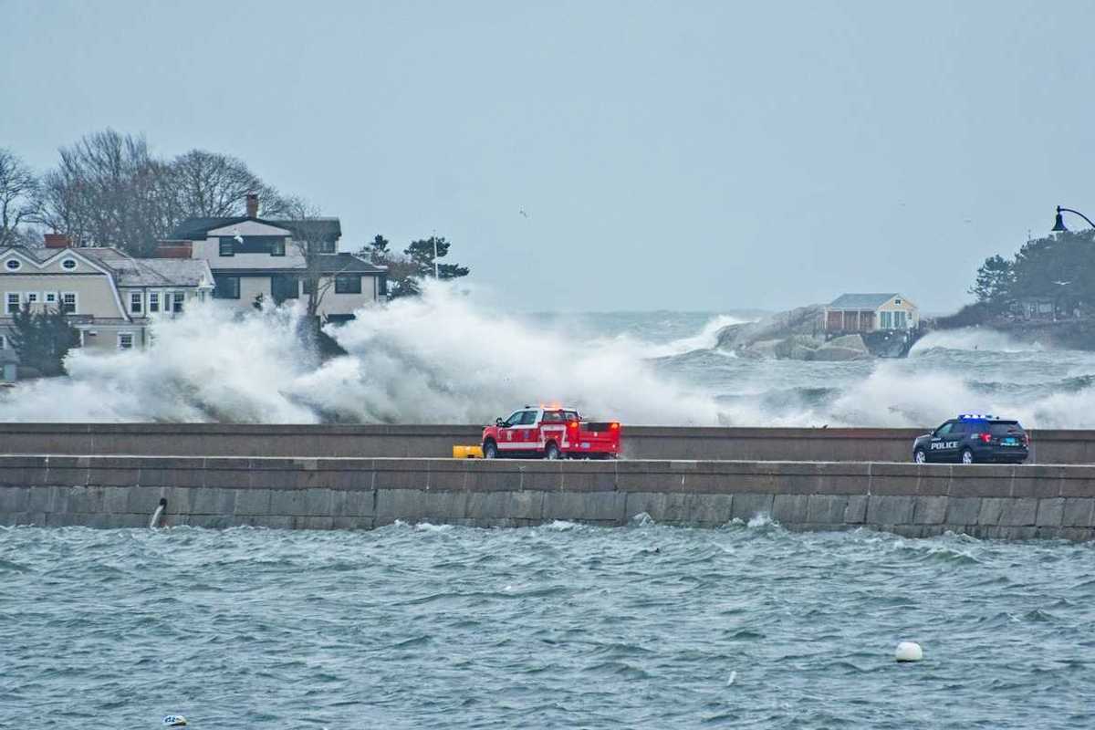 Emergency vehicles — pickup truck and police vehicle traveling amidst with storm-whipped surf
