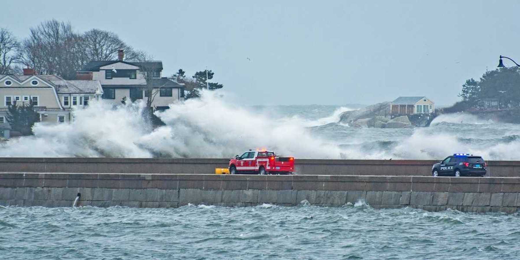 Emergency vehicles — pickup truck and police vehicle traveling amidst with storm-whipped surf