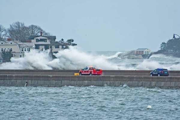 Emergency vehicles — pickup truck and police vehicle traveling amidst with storm-whipped surf