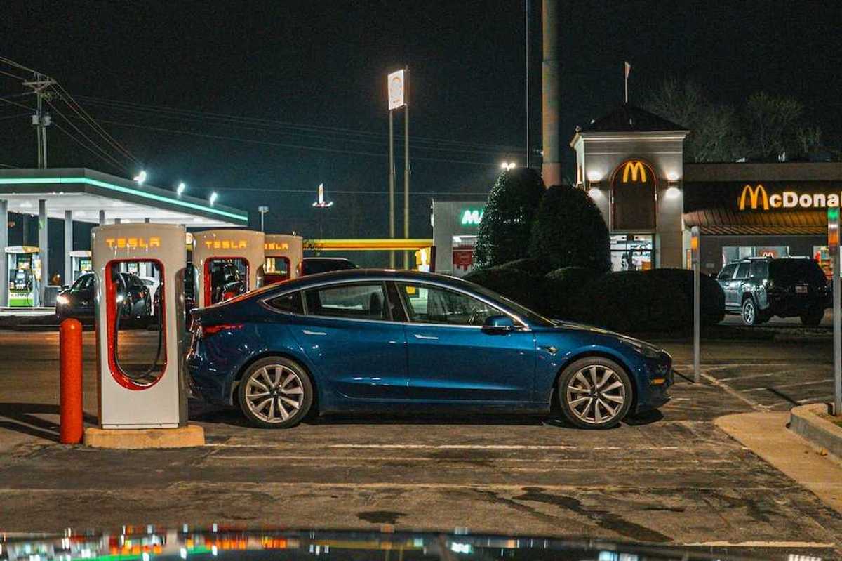 EV parked at a Tesla charging station adjacent to a MacDonald's restaurant