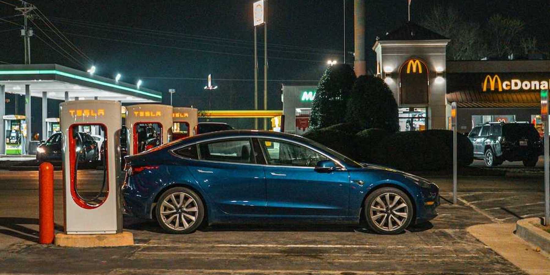 EV parked at a Tesla charging station adjacent to a MacDonald's restaurant